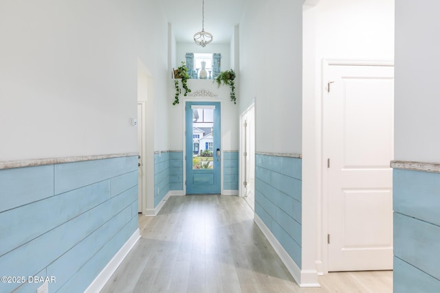 foyer entrance with a high ceiling, tile walls, and light wood-type flooring