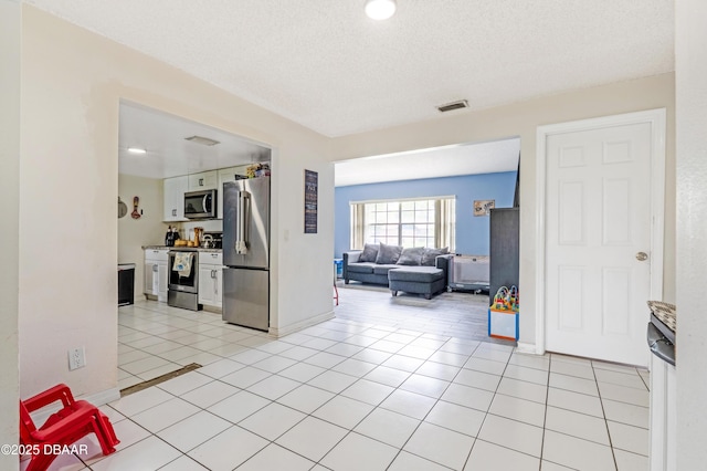 3618 Dame St, Port Orange, FL 32129 - kitchen with stainless steel appliances, light tile patterned flooring, open floor plan, white cabinetry, and a textured ceiling