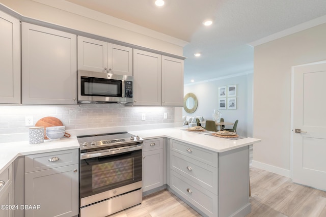 kitchen featuring crown molding, light wood-type flooring, tasteful backsplash, kitchen peninsula, and stainless steel appliances