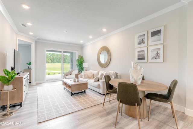 dining space featuring crown molding, light hardwood / wood-style flooring, and a textured ceiling