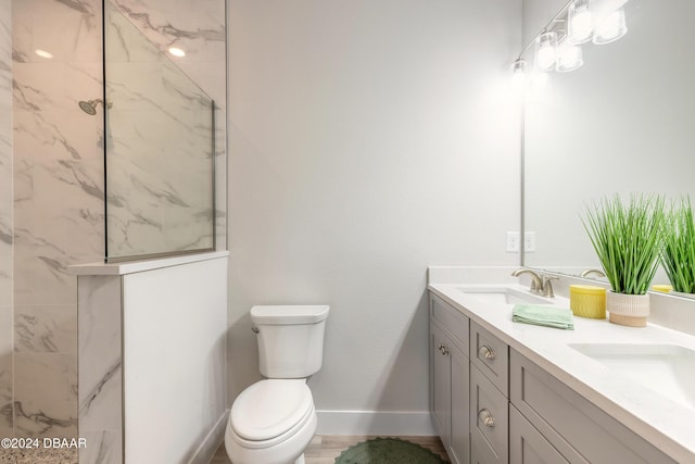 bathroom with vanity, toilet, and tiled shower