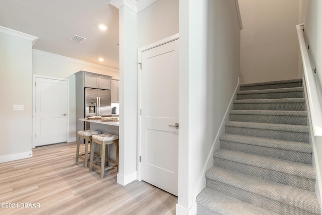 stairs featuring hardwood / wood-style floors and ornamental molding