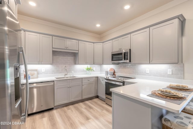 kitchen featuring sink, tasteful backsplash, kitchen peninsula, light hardwood / wood-style floors, and appliances with stainless steel finishes