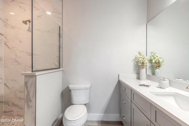 bathroom featuring a tile shower, vanity, and toilet