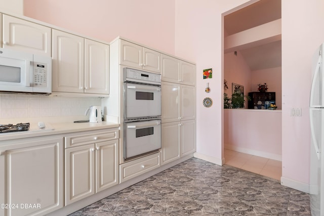 kitchen with white appliances, lofted ceiling, and tasteful backsplash