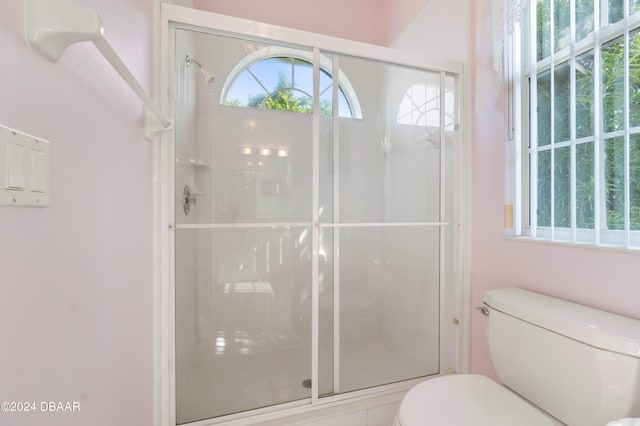 bathroom featuring toilet and a shower with shower door