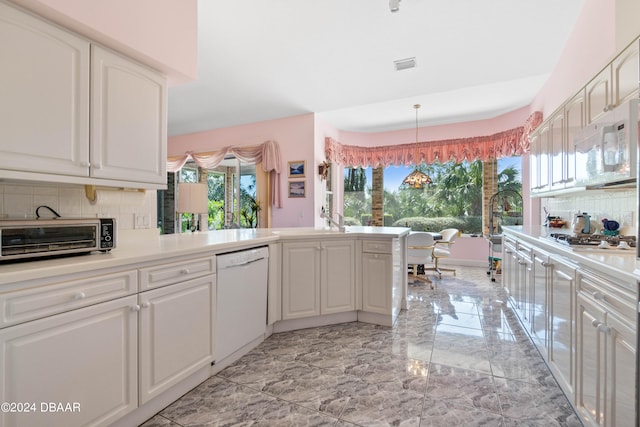 kitchen with pendant lighting, white cabinetry, tasteful backsplash, and white appliances