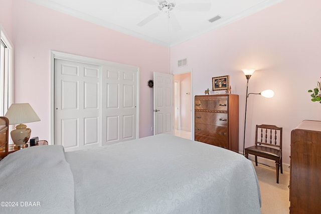 carpeted bedroom featuring ornamental molding, a closet, and ceiling fan