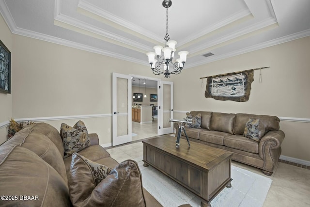 living room featuring light tile patterned floors, a tray ceiling, a chandelier, and ornamental molding