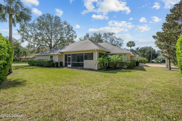 rear view of property featuring a yard, a sunroom, and stucco siding