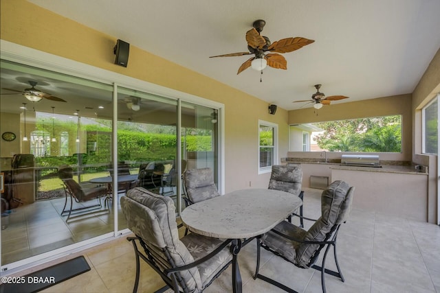 view of patio with exterior kitchen, outdoor dining area, area for grilling, and a ceiling fan