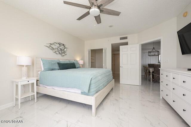 bedroom with marble finish floor, visible vents, a textured ceiling, and baseboards