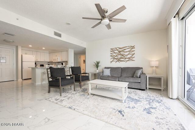 living area with a ceiling fan, marble finish floor, and visible vents