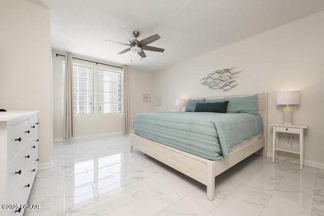 bedroom featuring ceiling fan, marble finish floor, and baseboards