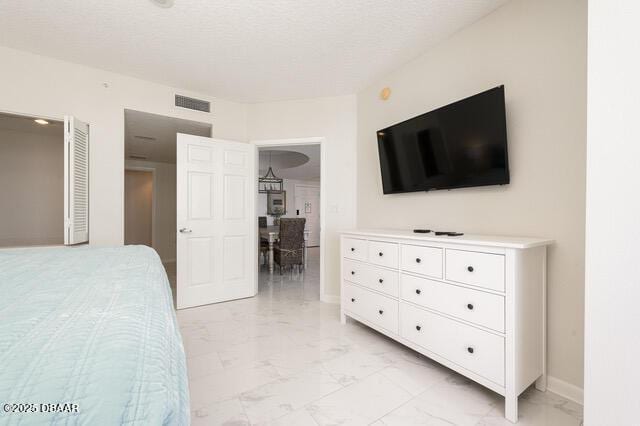 bedroom with marble finish floor, baseboards, visible vents, and a textured ceiling