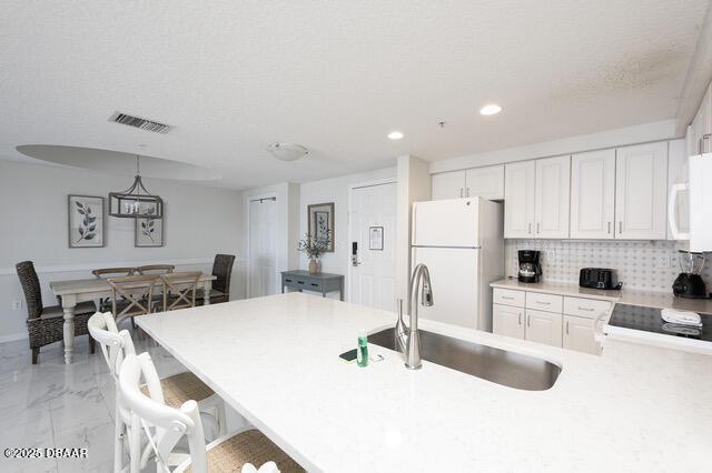 kitchen with marble finish floor, light countertops, visible vents, a sink, and white appliances