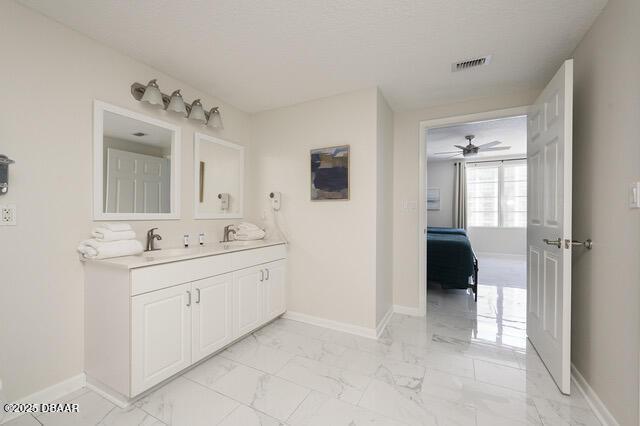 bathroom featuring marble finish floor, a sink, visible vents, and baseboards