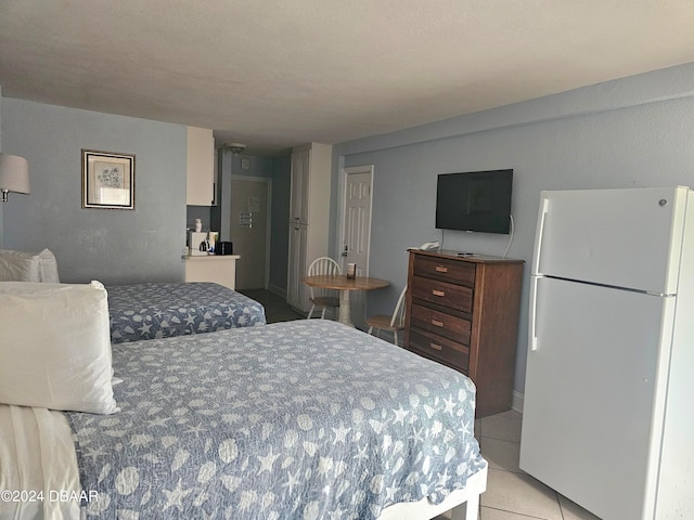 bedroom with light tile patterned floors, a textured ceiling, and white fridge