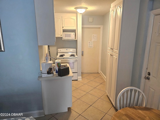 kitchen with white appliances, white cabinetry, light tile patterned floors, and a textured ceiling