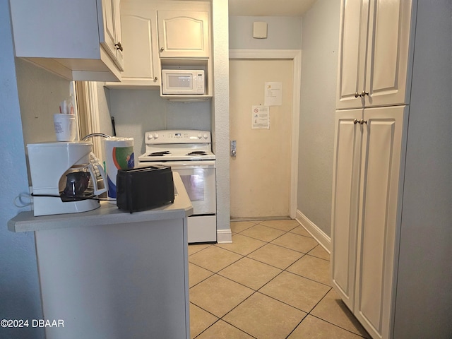 kitchen with white appliances, light tile patterned floors, and white cabinets