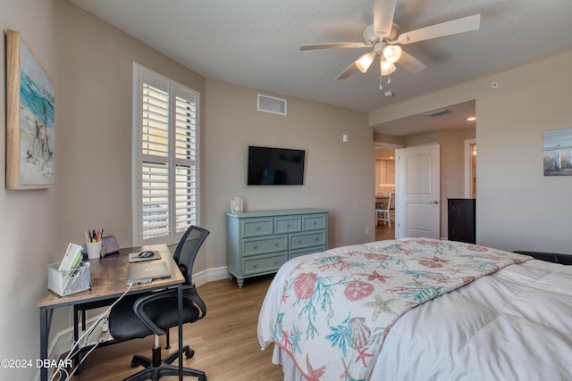 bedroom featuring ceiling fan, light hardwood / wood-style floors, and a textured ceiling