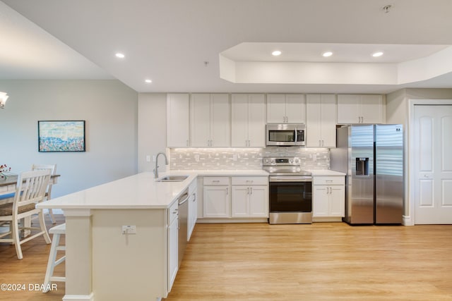 kitchen featuring kitchen peninsula, appliances with stainless steel finishes, tasteful backsplash, sink, and white cabinets