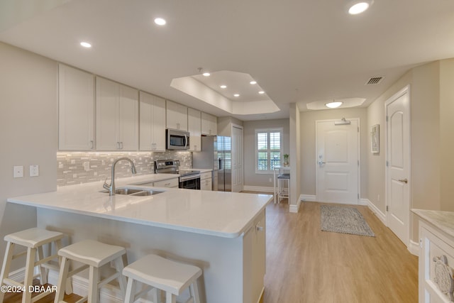 kitchen with white cabinets, stainless steel appliances, kitchen peninsula, and sink