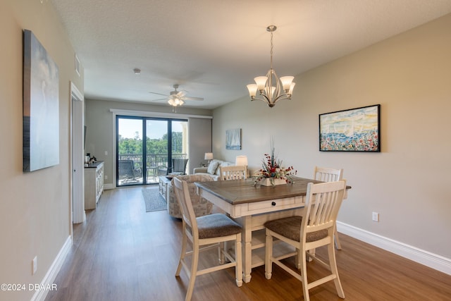 dining space with a textured ceiling, dark hardwood / wood-style floors, and ceiling fan with notable chandelier