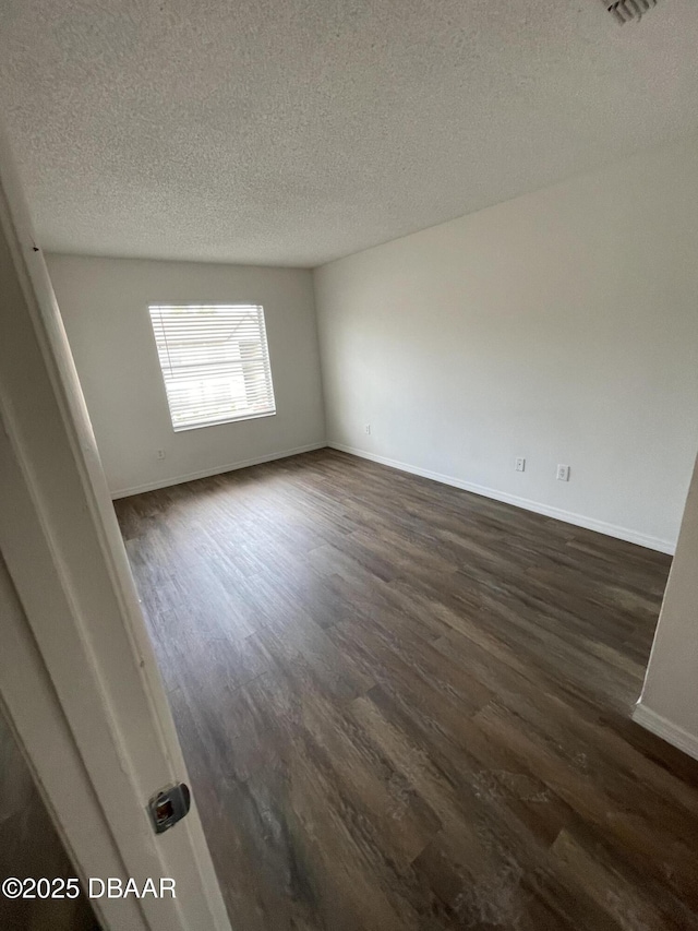 428 Banana Cay Dr Unit G, South Daytona, FL 32119 - empty room featuring dark wood-style floors, a textured ceiling, and baseboards