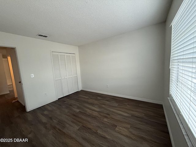428 Banana Cay Dr Unit G, South Daytona, FL 32119 - unfurnished bedroom featuring dark wood-style floors, multiple windows, a textured ceiling, a closet, and baseboards