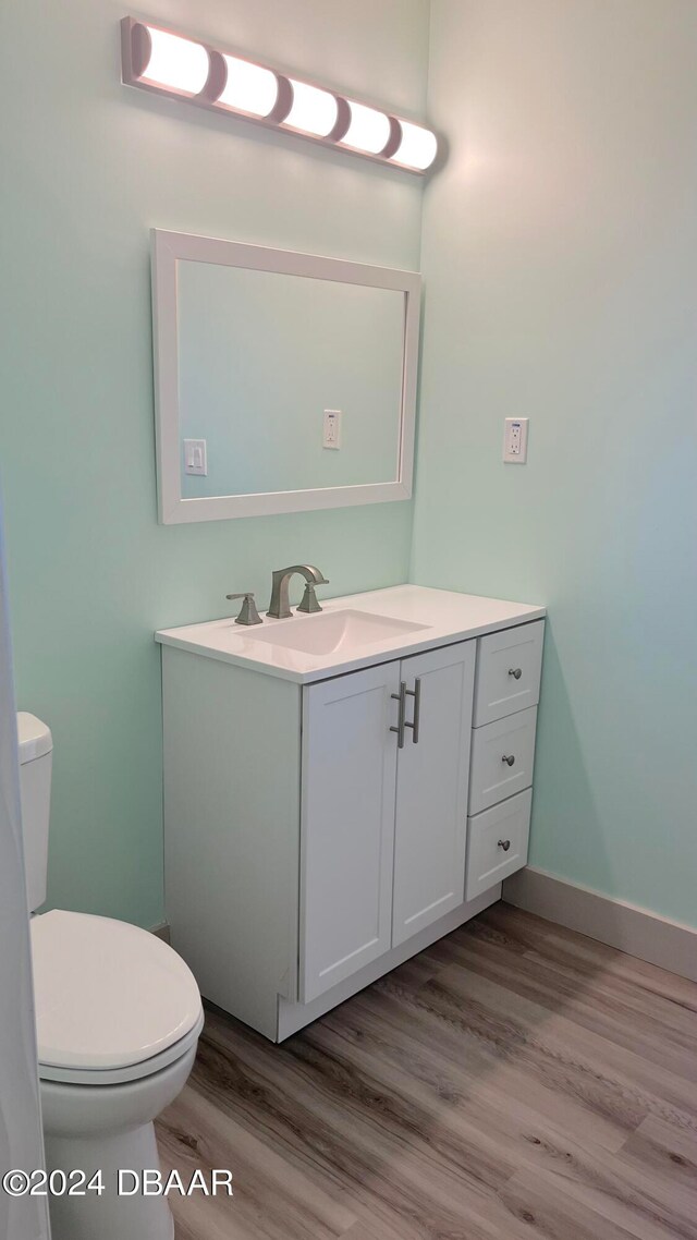 bathroom with hardwood / wood-style floors, vanity, and toilet