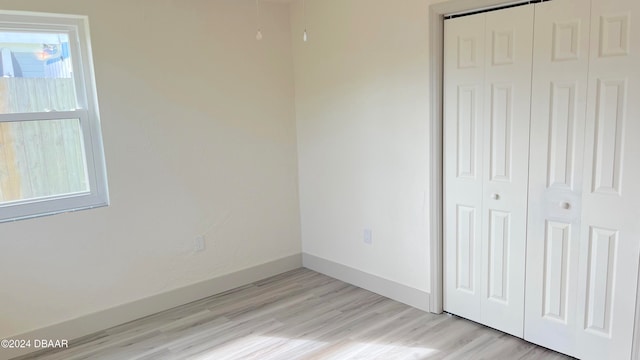 unfurnished bedroom with a closet, multiple windows, and light hardwood / wood-style floors