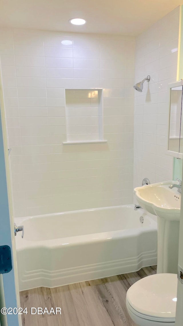 bathroom with wood-type flooring, toilet, and tiled shower / bath combo