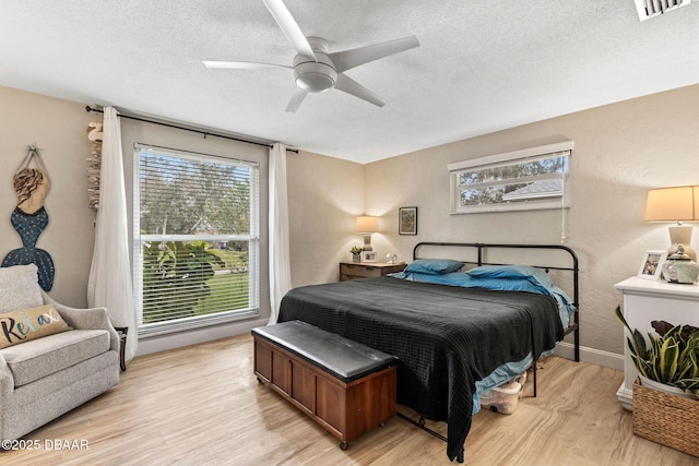 bedroom with light wood finished floors, multiple windows, and a textured ceiling