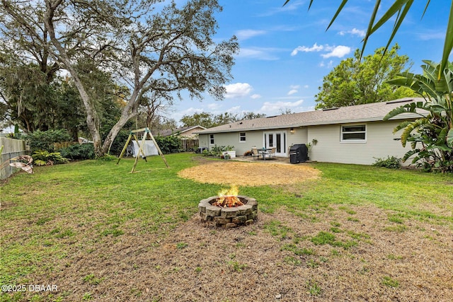 view of yard featuring a fire pit, french doors, a playground, and a fenced backyard