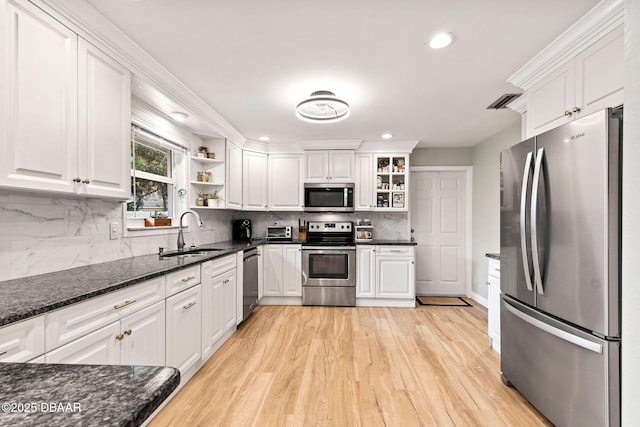 kitchen with dark stone counters, stainless steel appliances, white cabinetry, open shelves, and a sink