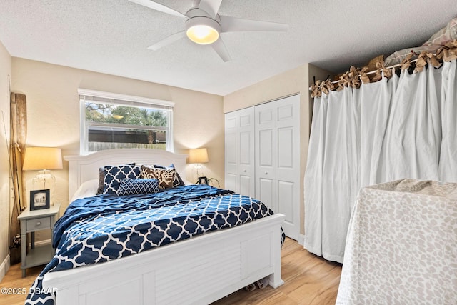 bedroom with a textured ceiling, a closet, a ceiling fan, and light wood-style floors