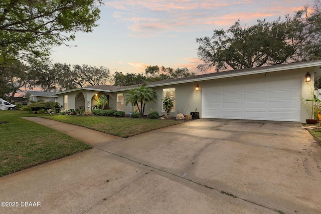 view of front of home with a front yard, concrete driveway, an attached garage, and stucco siding