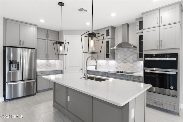 kitchen featuring stainless steel appliances, wall chimney range hood, sink, and pendant lighting