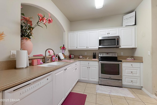 kitchen featuring appliances with stainless steel finishes, white cabinetry, sink, light tile patterned floors, and kitchen peninsula