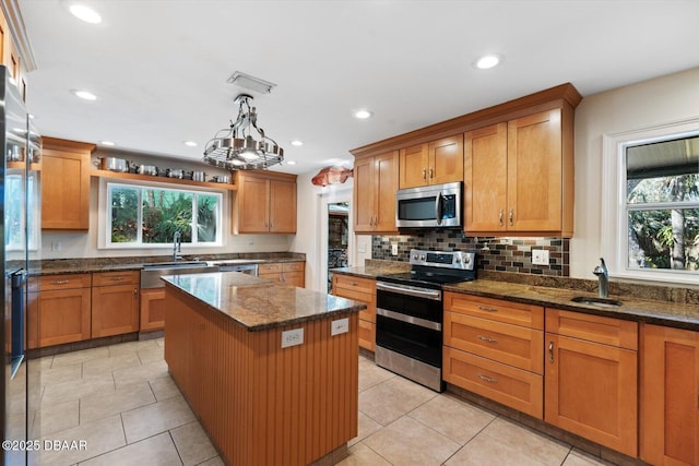 kitchen with pendant lighting, sink, stainless steel appliances, and a center island