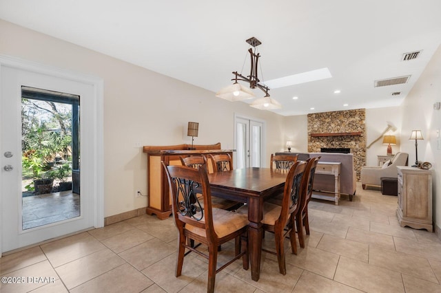 tiled dining area with a fireplace and a skylight