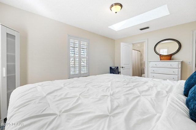 bedroom with connected bathroom and a skylight