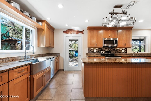 kitchen featuring plenty of natural light, stainless steel appliances, a kitchen island, and stone counters