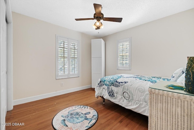 bedroom featuring ceiling fan, hardwood / wood-style floors, and a textured ceiling