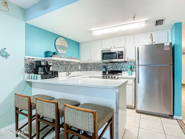 kitchen featuring tasteful backsplash, white cabinetry, appliances with stainless steel finishes, and sink