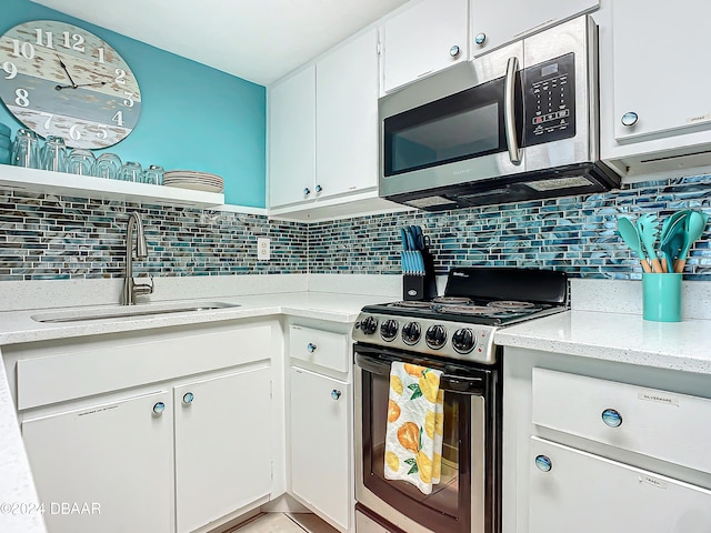 kitchen with light stone counters, white cabinets, sink, tasteful backsplash, and appliances with stainless steel finishes