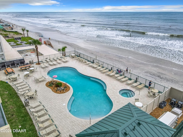 view of pool featuring a beach view, a water view, and a patio area