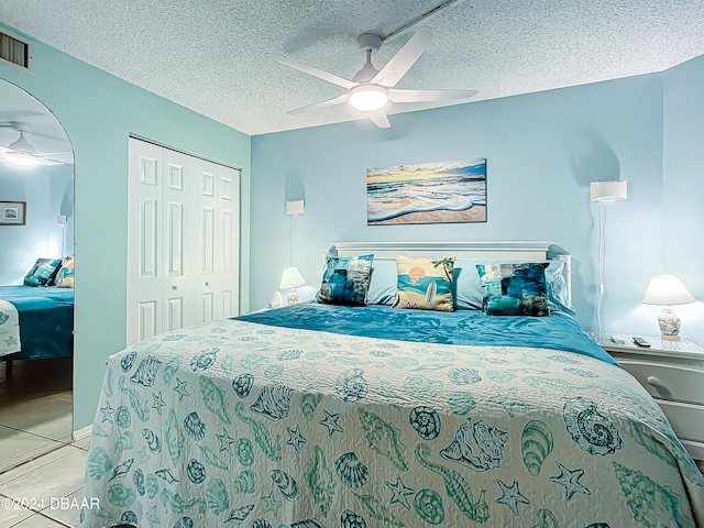 tiled bedroom with ceiling fan, a textured ceiling, and a closet