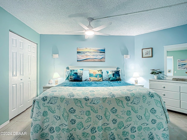 tiled bedroom with a textured ceiling, ceiling fan, and a closet